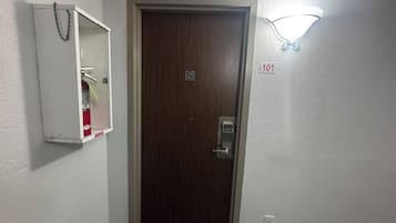 A door with a digital lock, a fire extinguisher, and a wall-mounted light fixture.