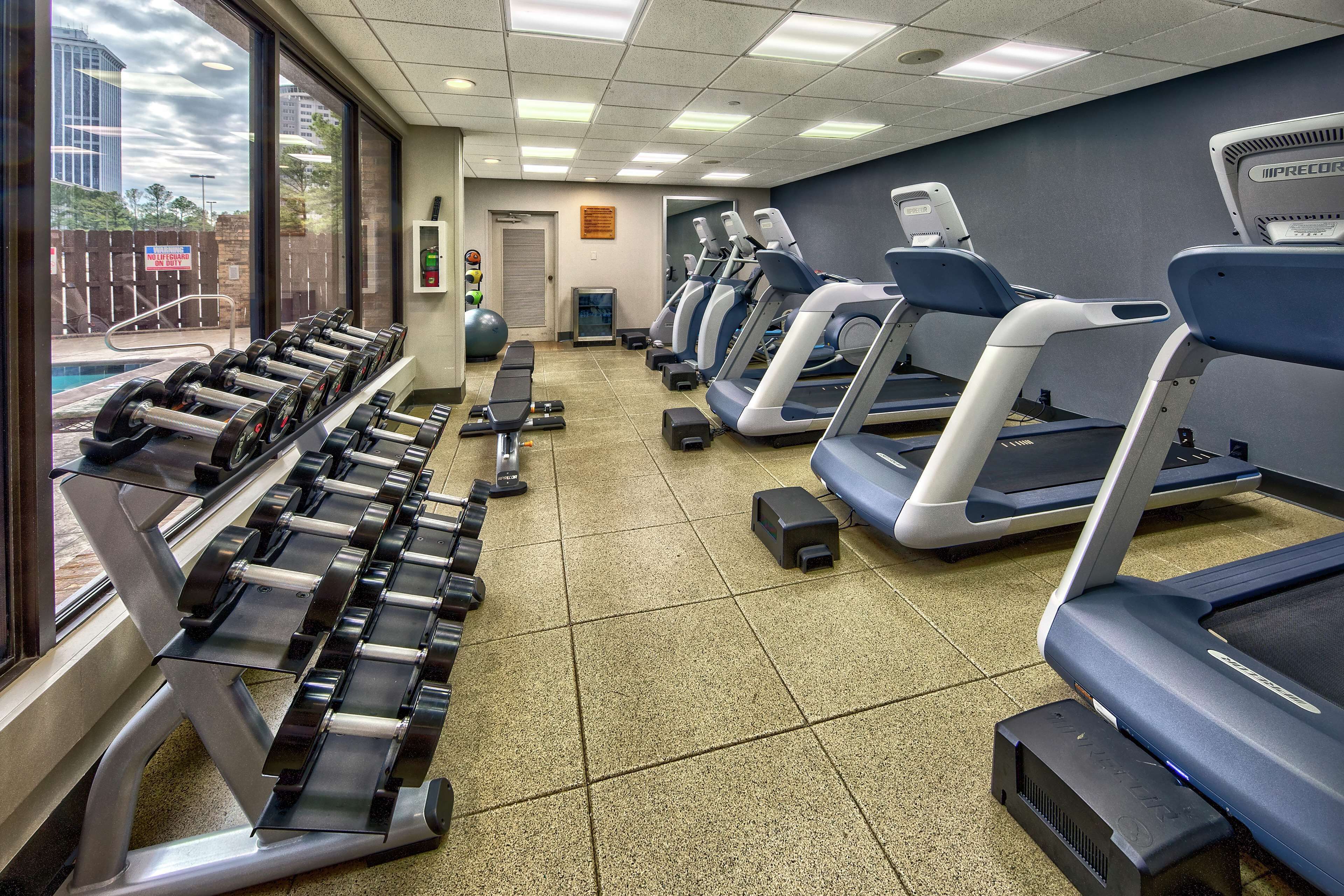 Une salle de sport équipée de tapis de course, d’haltères et de ballons d’exercice.