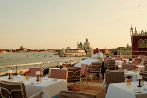 Una terrazza con tavoli e sedie che si affaccia su una banchina con edifici storici.