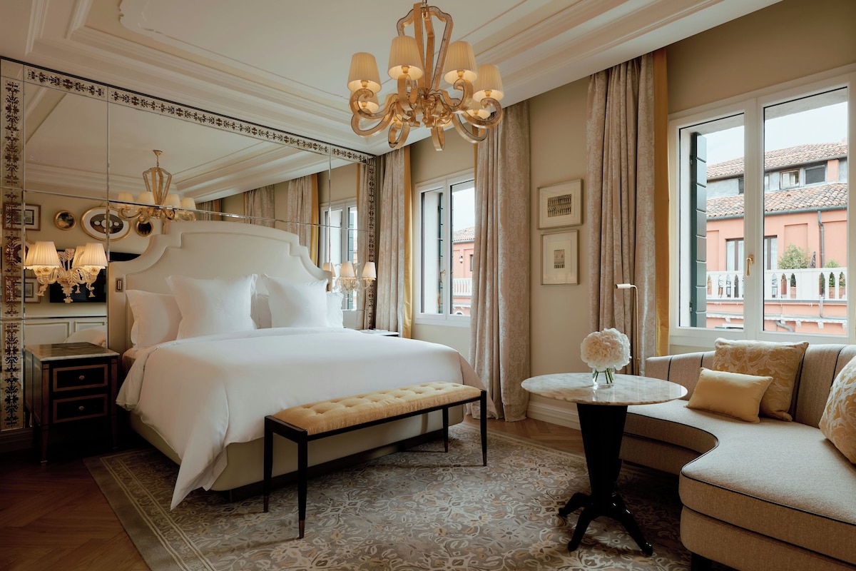 Una camera d'albergo con un letto grande, un divano, un tavolino e vista sulla città.