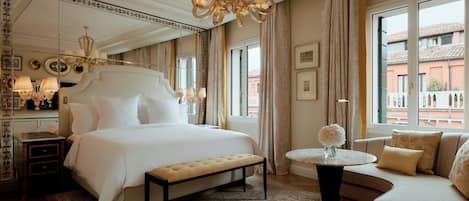 Habitación de hotel con una cama grande, un sofá, una mesita y vistas a la ciudad.