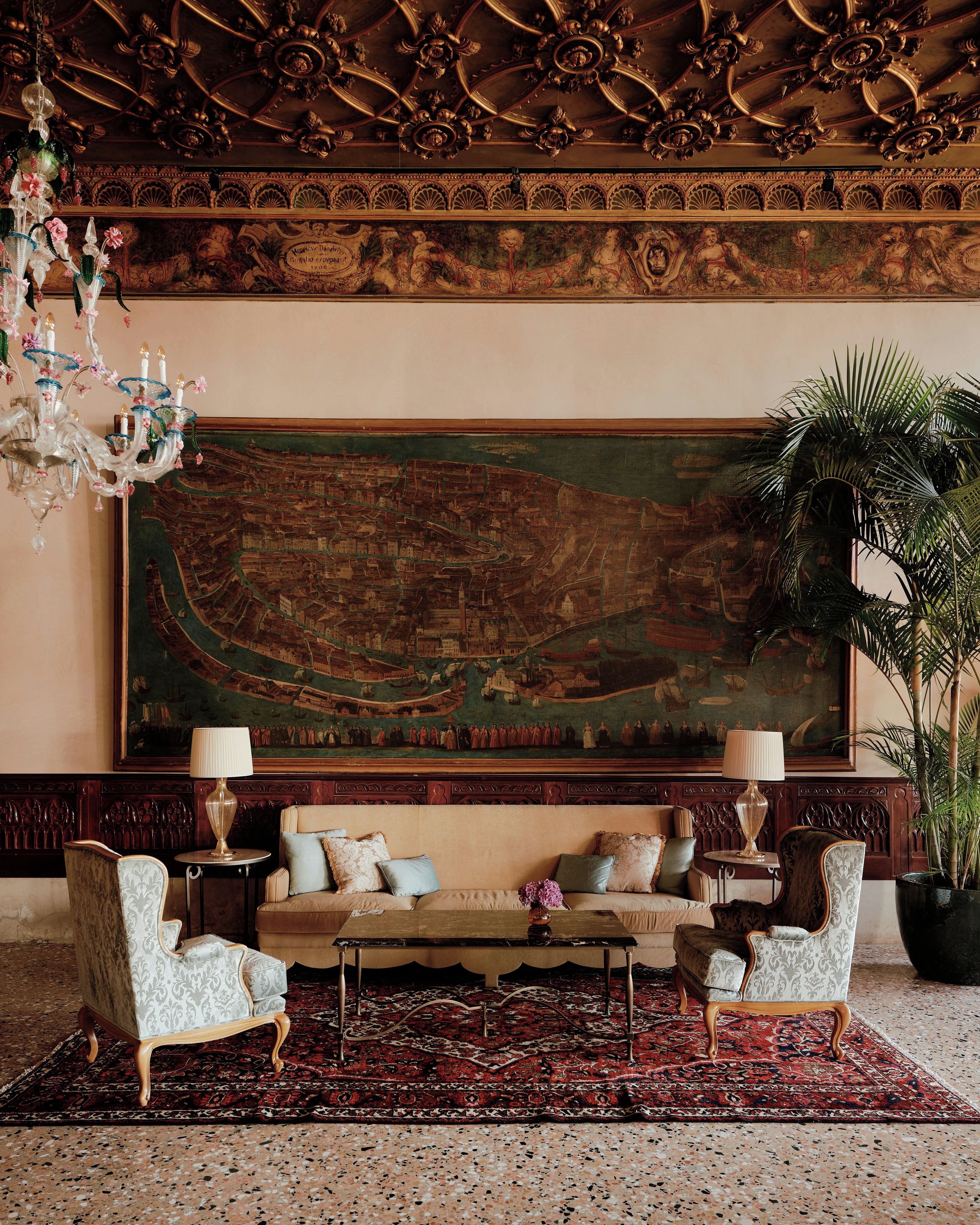 Une pièce agrémentée d’un grand tableau décoratif, d’un lustre et d’un ensemble de meubles de salon.