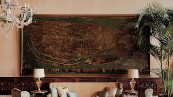 Une pièce agrémentée d’un grand tableau décoratif, d’un lustre et d’un ensemble de meubles de salon.