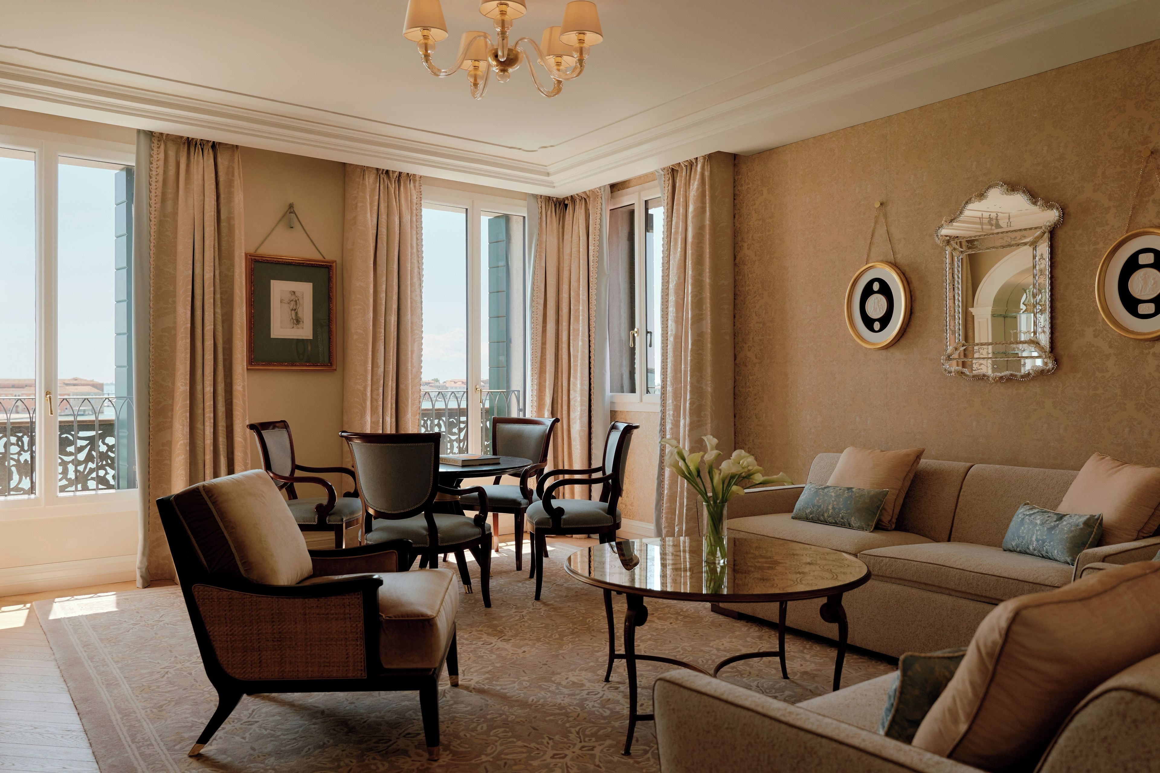 Un salon bien éclairé, avec un canapé, des fauteuils, une table basse et un lustre.