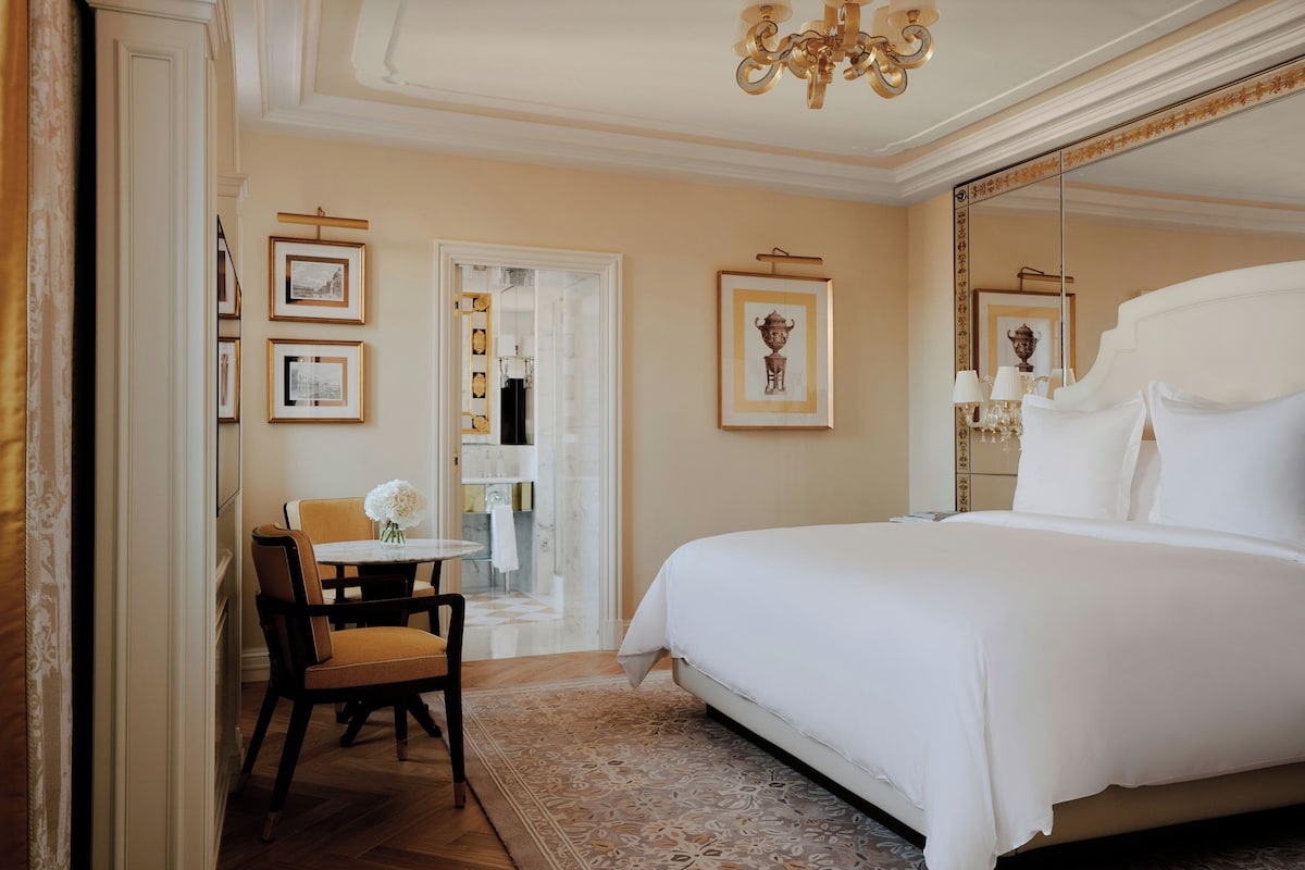 Una camera d'albergo con un letto grande, un tavolo da pranzo con sedie e uno specchio.