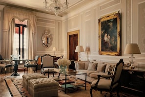 A classic room with a large painting, elegant furniture, and a chandelier.