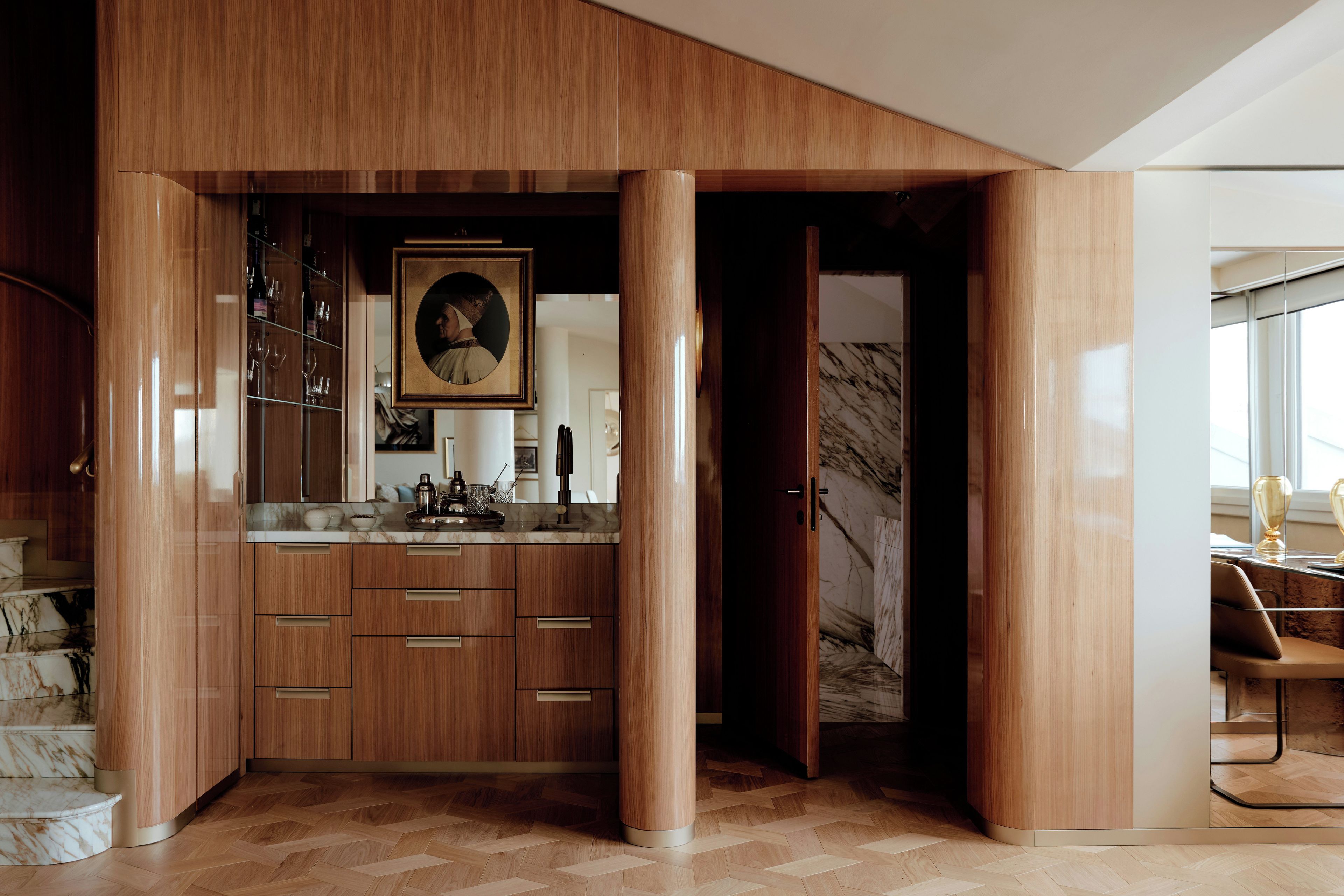 A modern kitchen with wooden cabinetry, a marble countertop, and a large framed artwork.