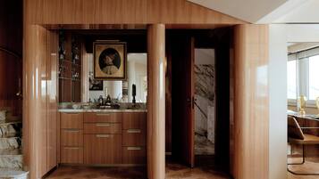 A modern kitchen with wooden cabinetry, a marble countertop, and a large framed artwork.