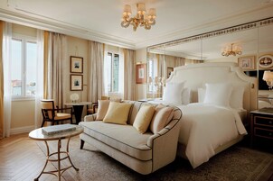 Un'ampia camera da letto con un grande letto, una zona relax con divano e vista sul mare dalla finestra.