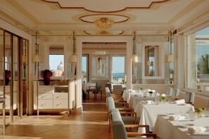 A spacious dining area with high ceilings, elegant chandeliers, and a view of the sea. - Danieli, Venezia, A Four Seasons Hotel (Venice)