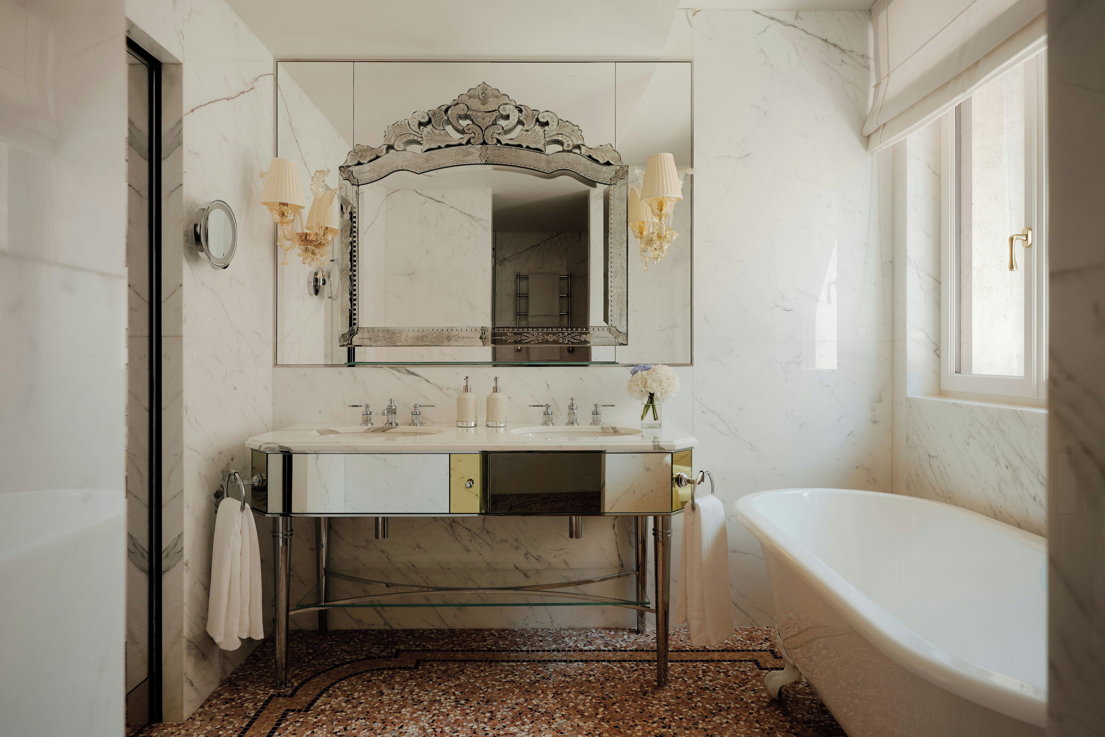 Une salle de bain avec un meuble-lavabo en marbre, un grand miroir, une baignoire et un espace douche.