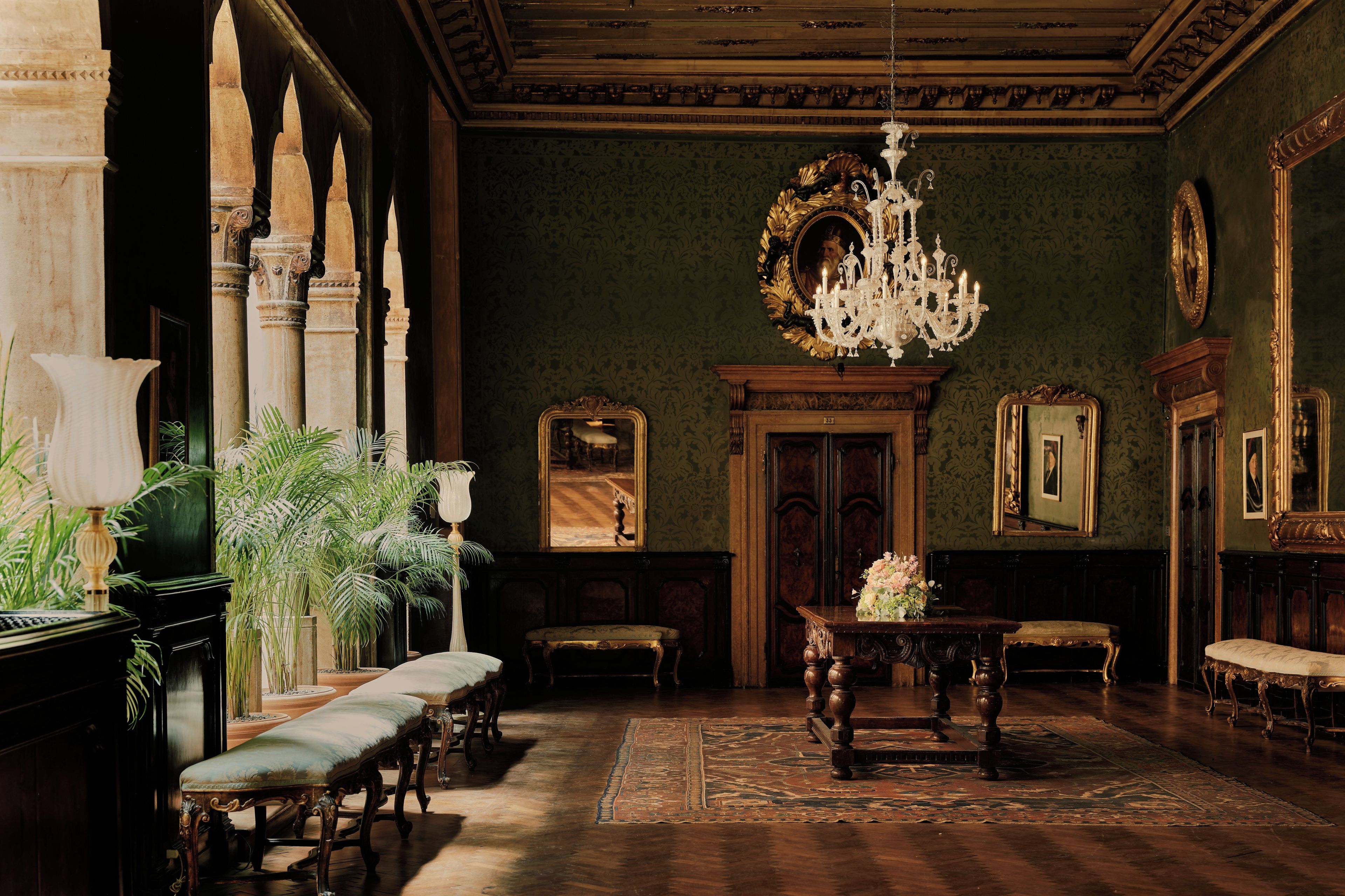 A grand room with a chandelier, ornate furniture, and a large mirror.
