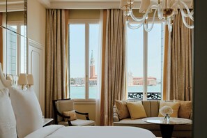 Une chambre d’hôtel avec un lit, une chaise, un canapé, une table et une vue sur le paysage urbain, visible à travers de grandes fenêtres.