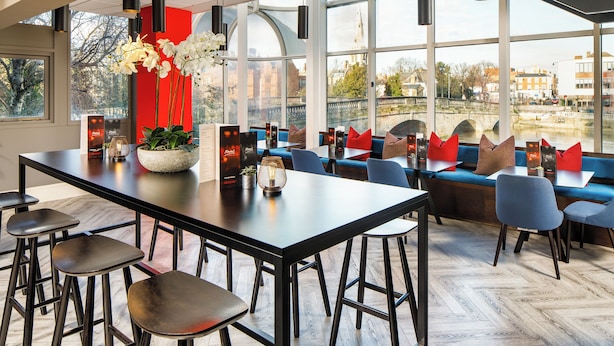 Ein modernes Restaurant mit einem langen Tisch, Barhocker und blauen Sitzgelegenheiten.