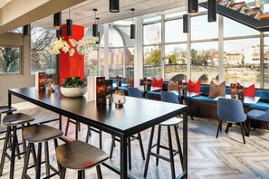 Een modern restaurant met een lange tafel, barkrukken en blauwe zitplaatsen.