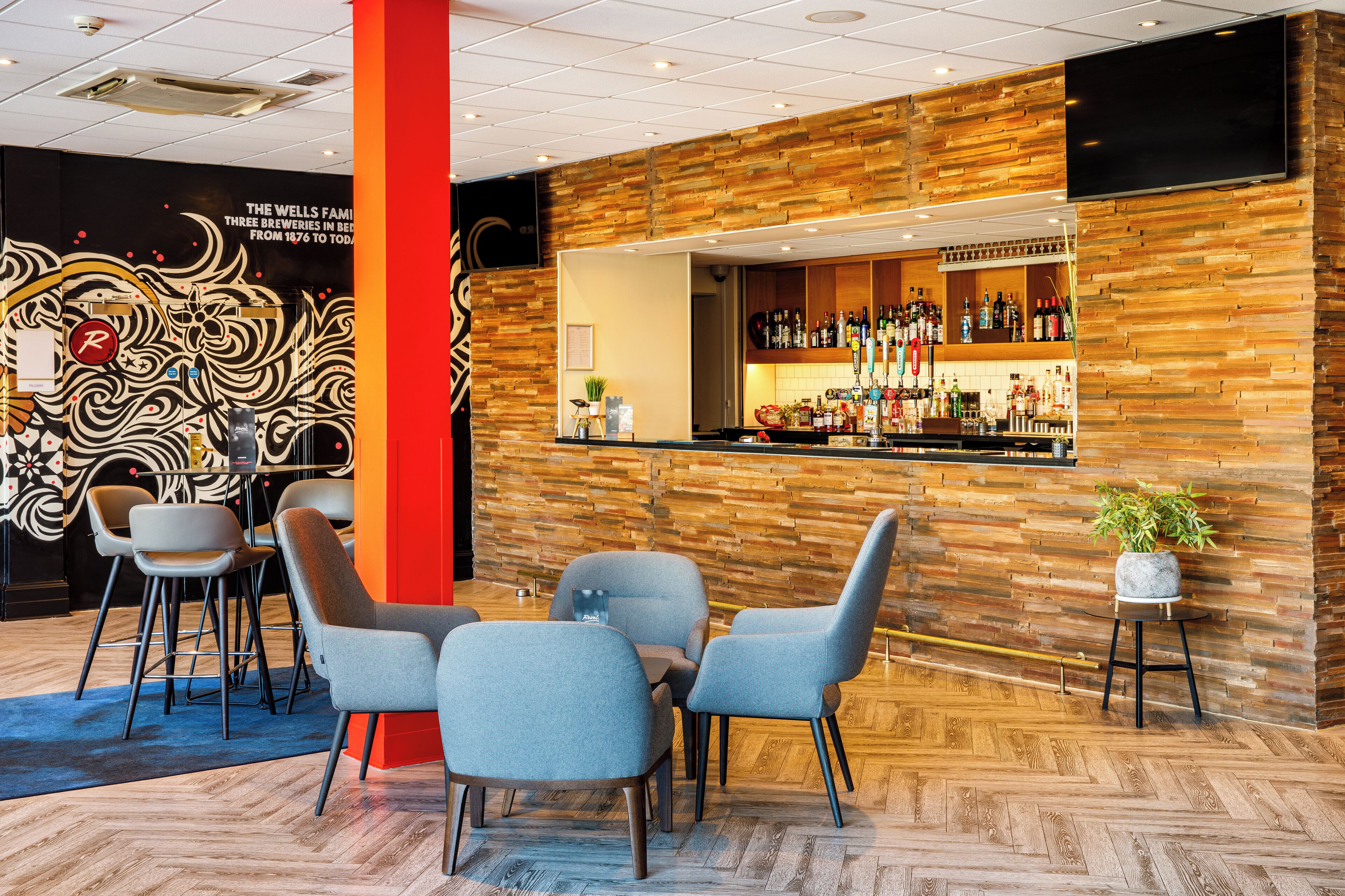 Zona de bar con pared de madera, taburetes y mostrador con varias botellas.