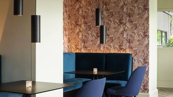 A modern dining area with a dark table, blue seating, and pendant lights.
