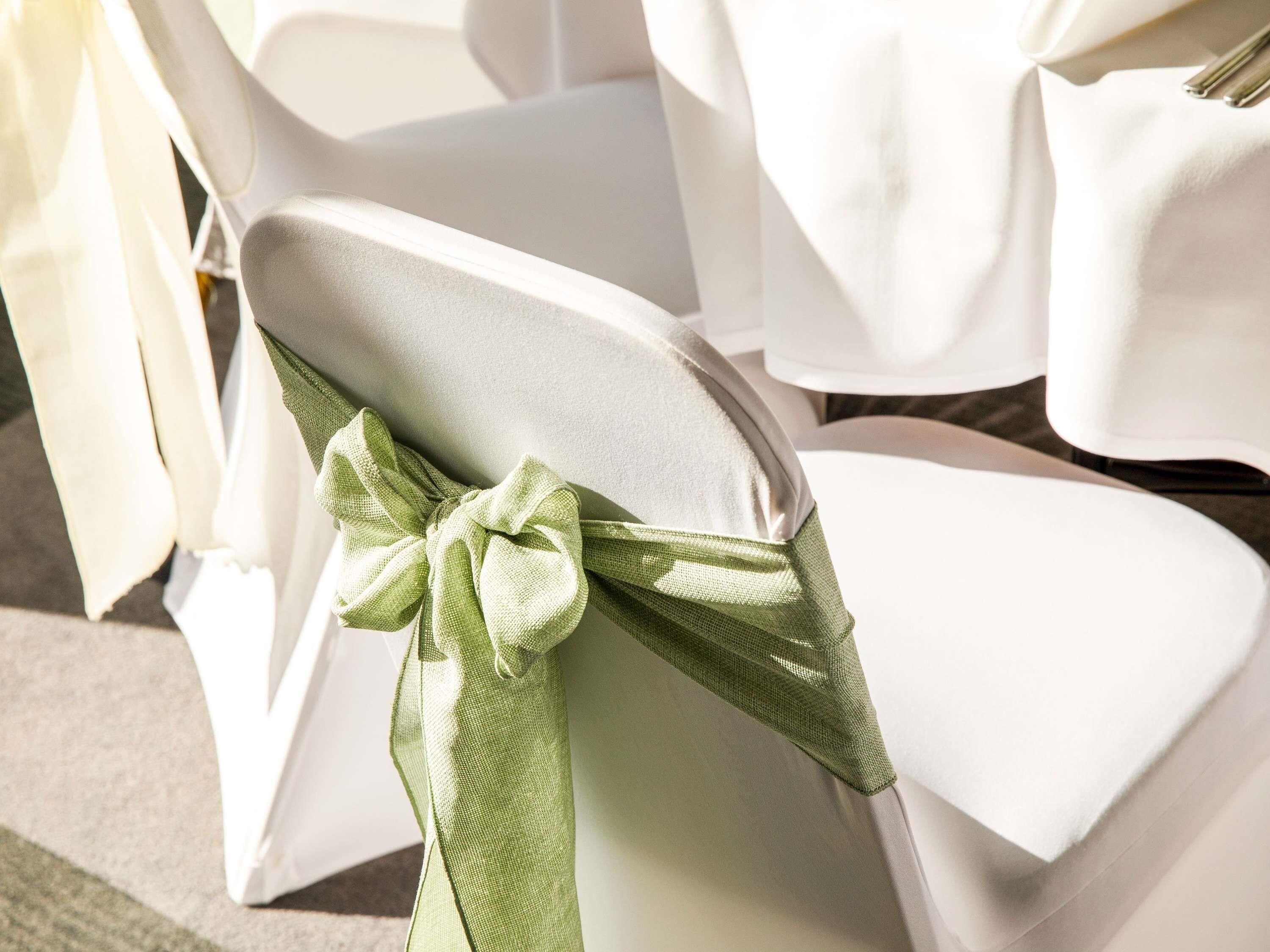 A chair with a white cover and a green bow.
