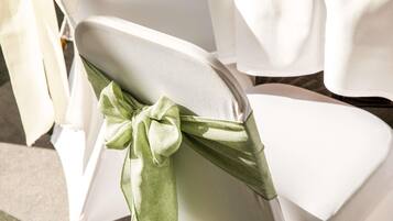 A chair with a white cover and a green bow.
