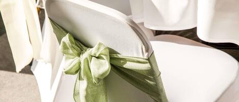 A chair with a white cover and a green bow.