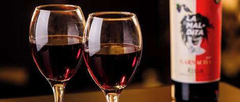 Two wine glasses on a table with a bottle of wine in the background.