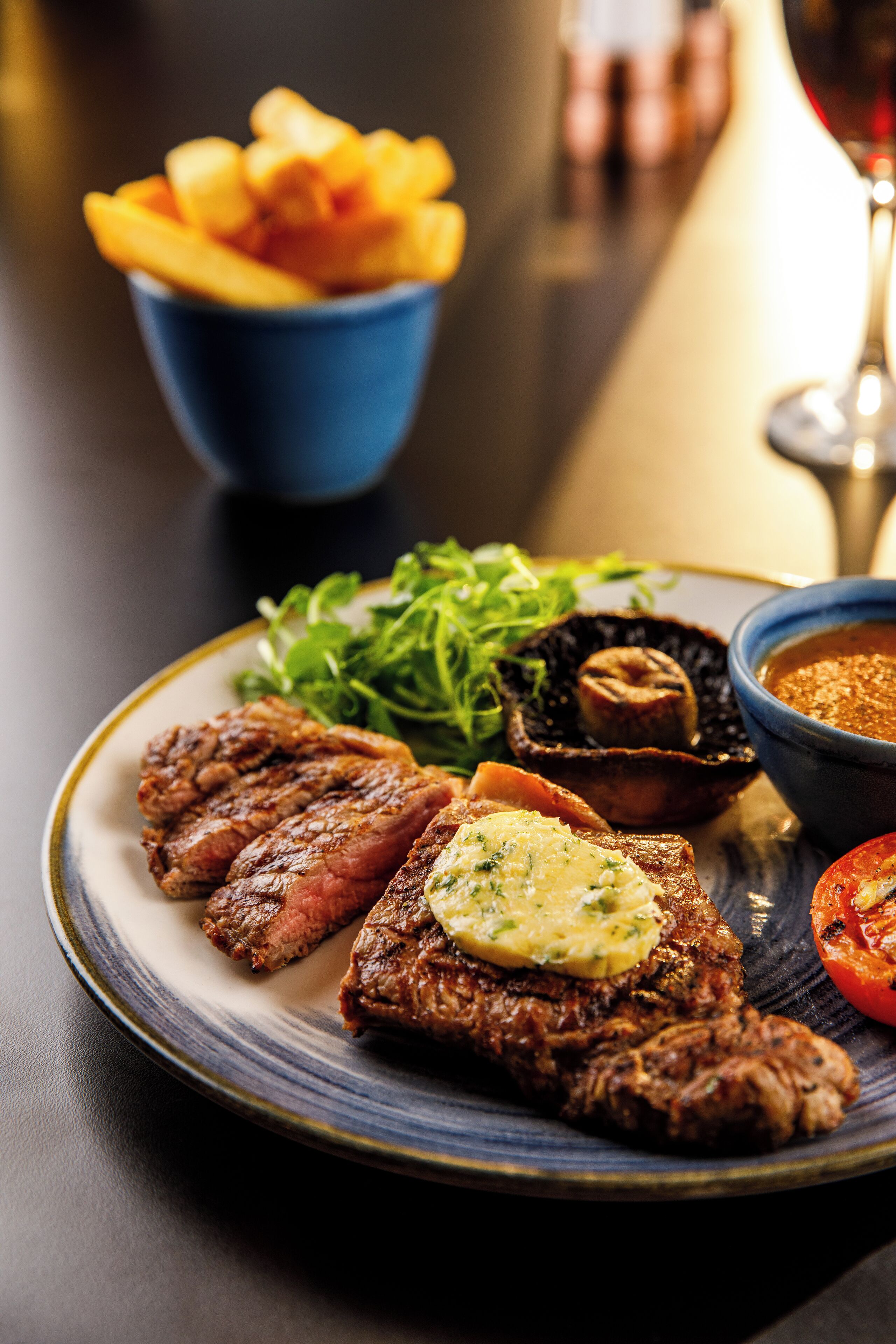 Um prato com bife, batatas fritas e legumes.