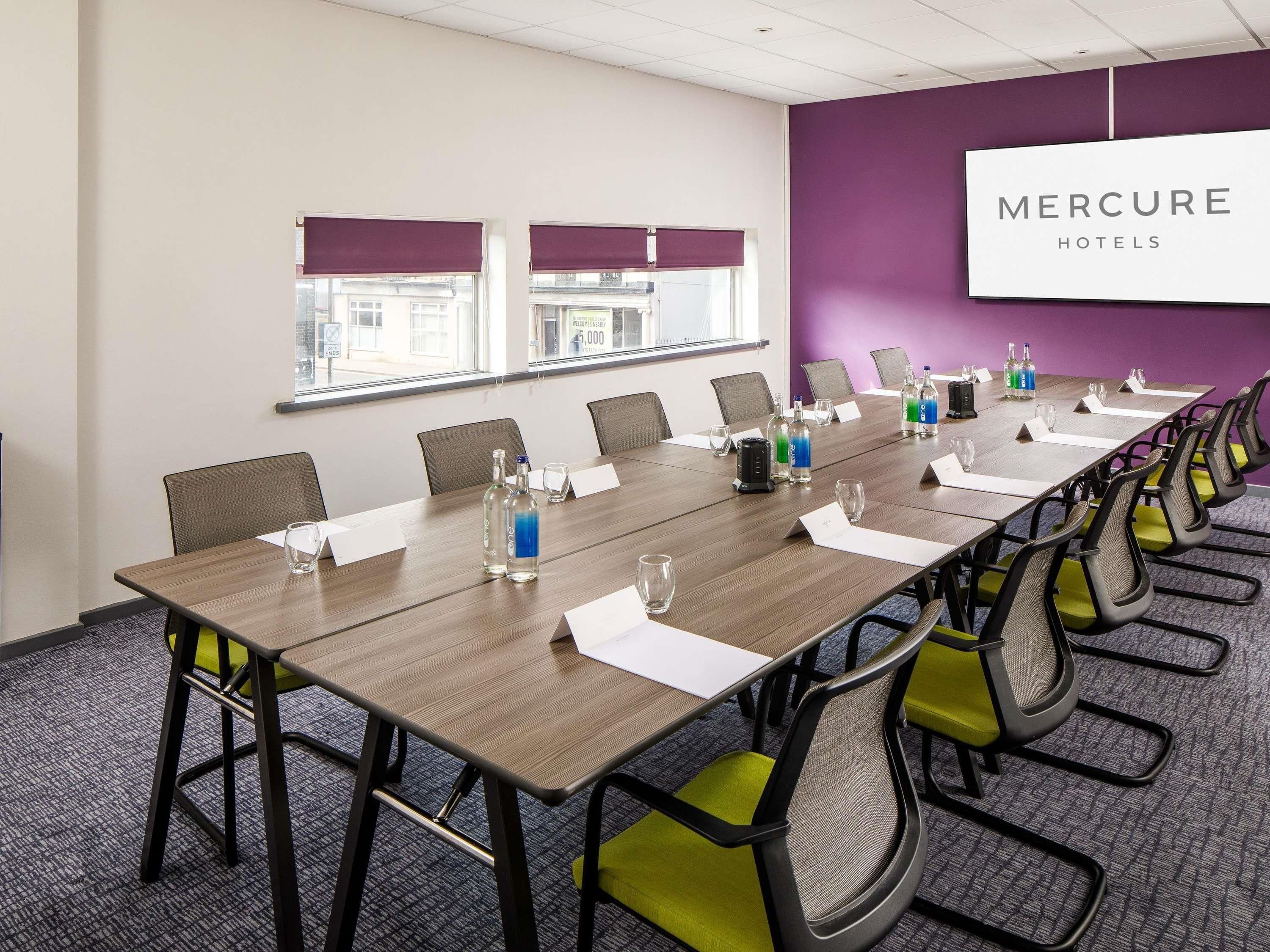 A conference room with a long table, chairs, and a sign for Mercure Hotels.