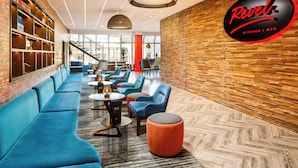 Ein stilvoller Lounge-Bereich mit blauen Sofas, runden Tischen und einem Fischgrätparkettboden.