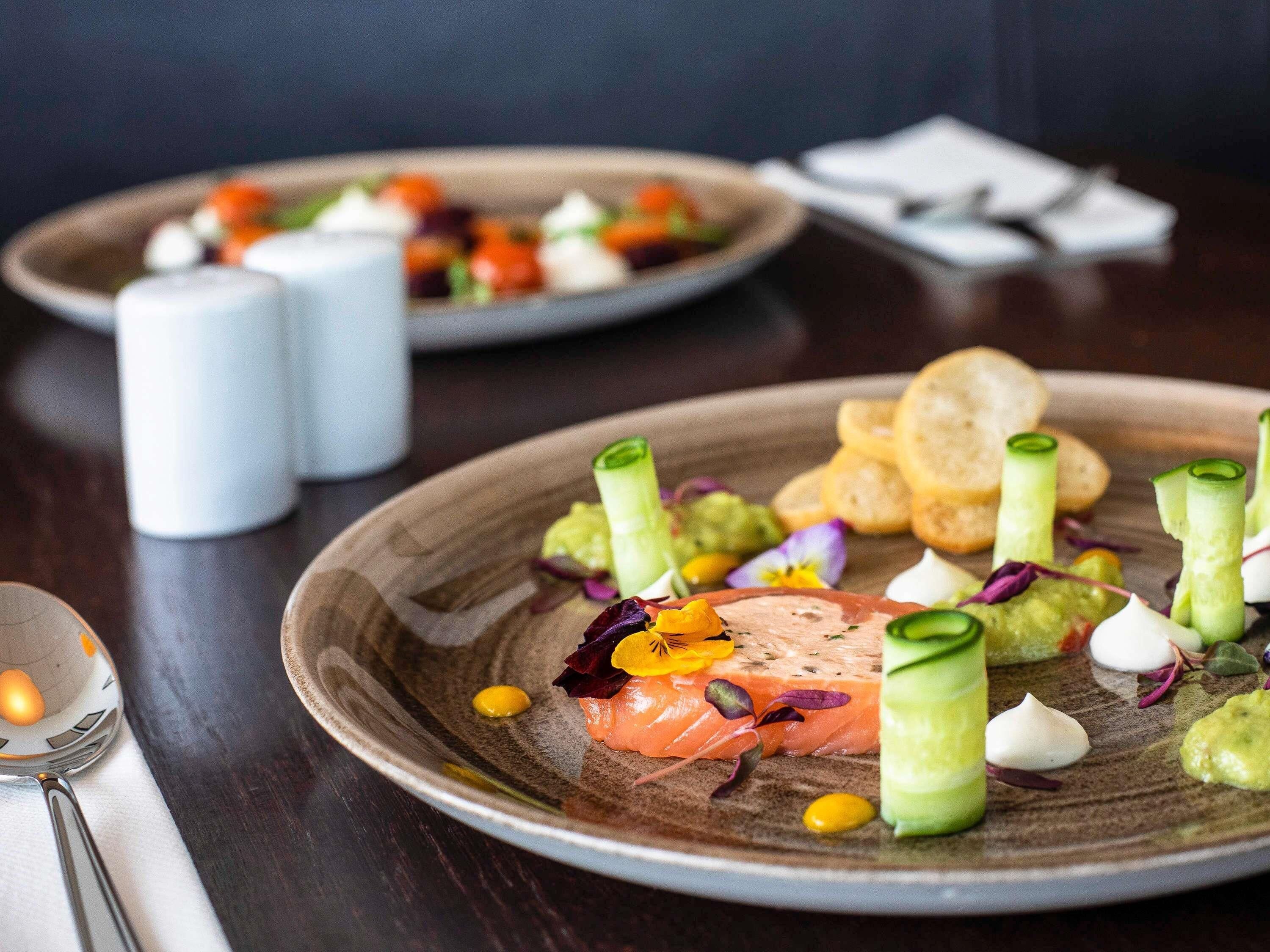 A plate of food with salmon, avocado, and garnishes.