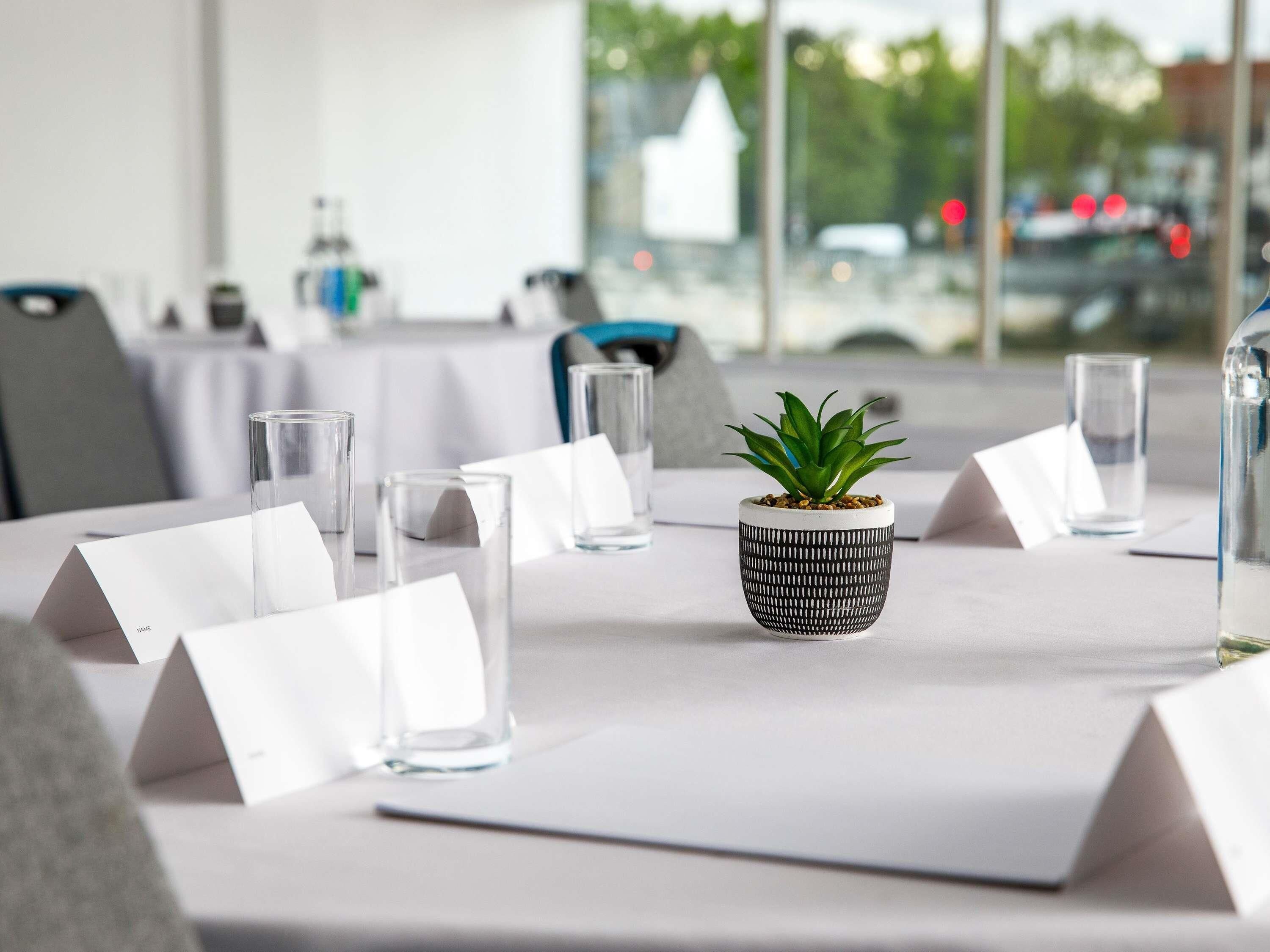 A conference table with name cards, glasses, and a potted plant.