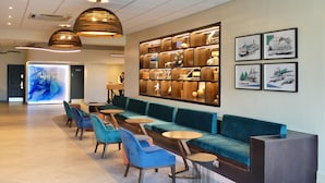 Eine moderne Hotellobby mit einer langen, türkisgrünen Couch, blauen Sesseln und einem Empfangstisch.