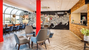 Un intérieur moderne avec un parquet en chevrons, un coin salon avec des fauteuils, un comptoir de bar et une fresque murale.