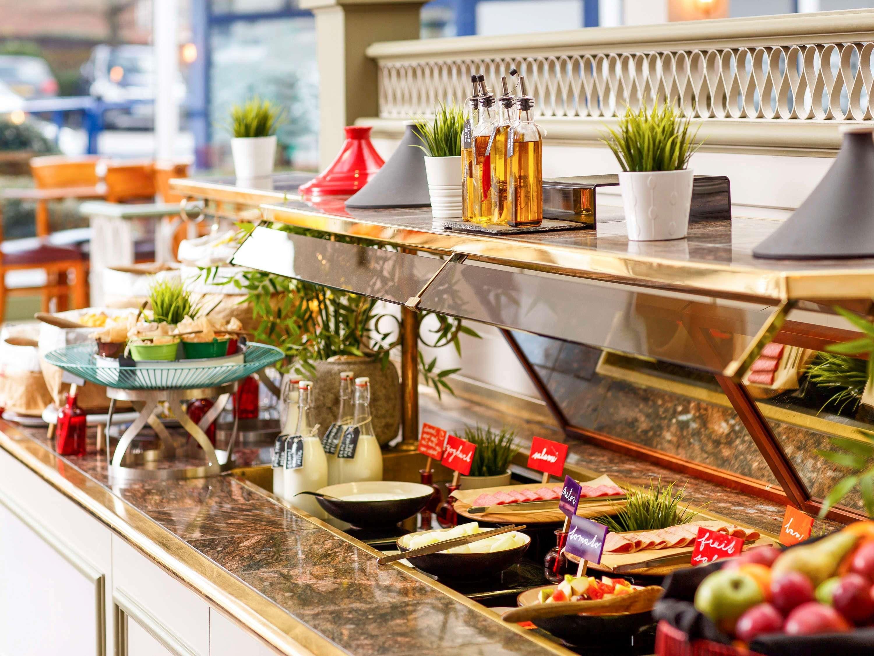 Een buffet met diverse gerechten en bijbehorende sauzen, waaronder een keuze uit kazen, fruit en vleeswaren.