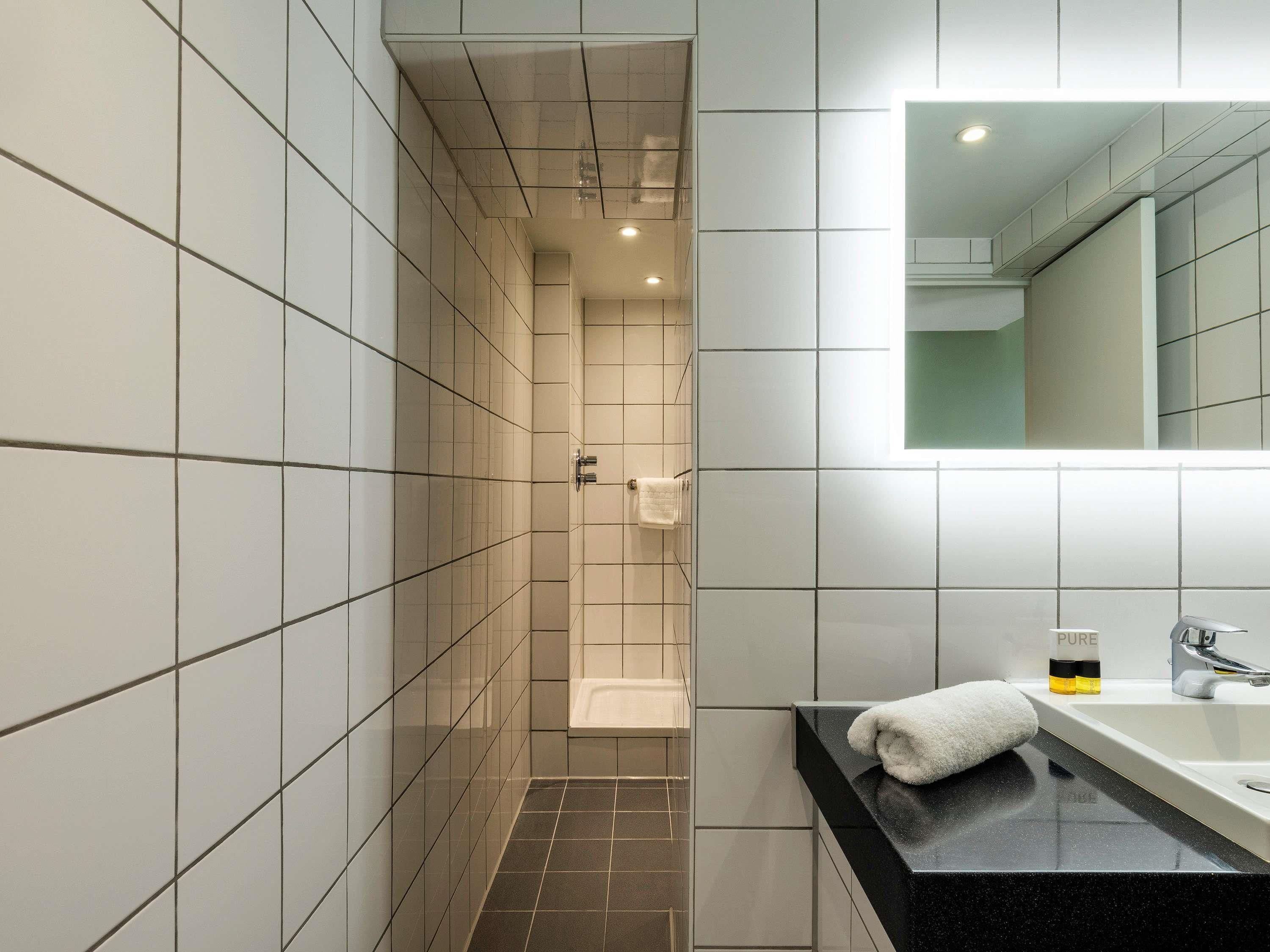 Een moderne badkamer met een douche, een wastafel en een spiegel.