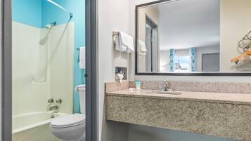 A bathroom with a shower, toilet, sink, and a large mirror.