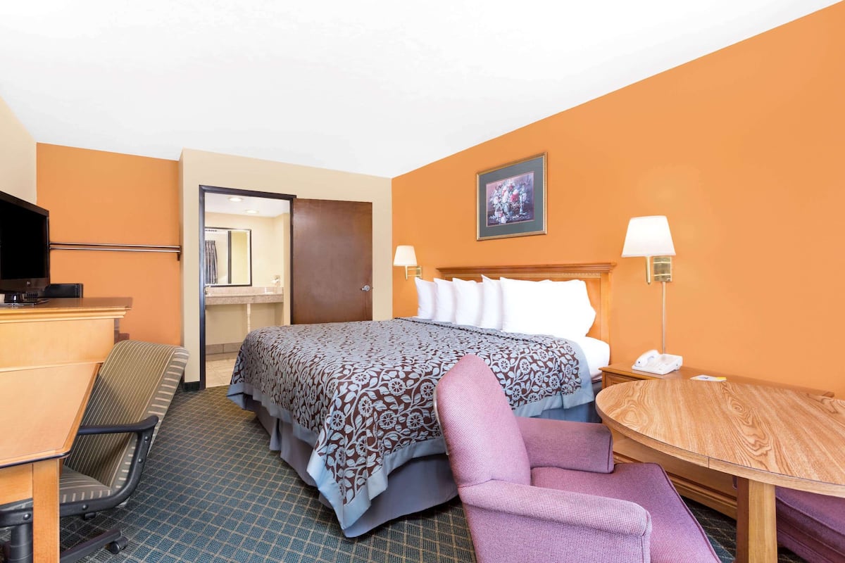 Ein Hotelzimmer mit einem Bett, einem Schreibtisch, einem Sessel, einem kleinen Tisch und einem Fernseher.