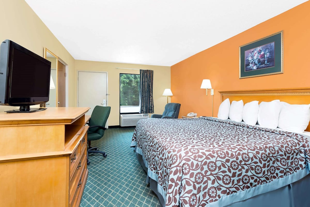 Ein Hotelzimmer mit Bett, Schreibtisch, Stuhl und Fernseher.