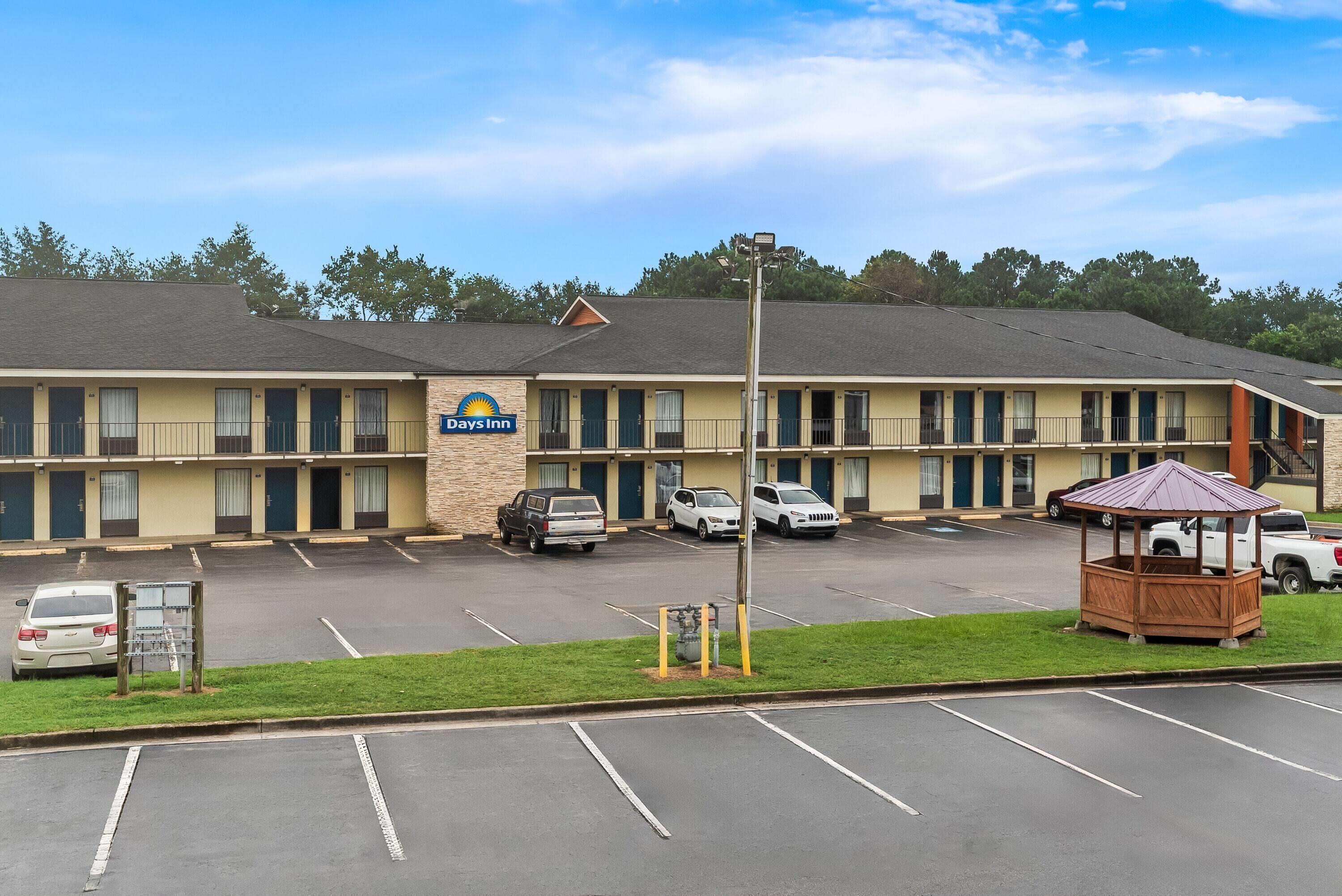 A Days Inn with a parking lot, a gazebo, and a building with multiple doors and windows.