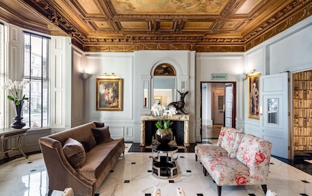 A grand room with a marble floor, a fireplace, a sofa, and a bookshelf.