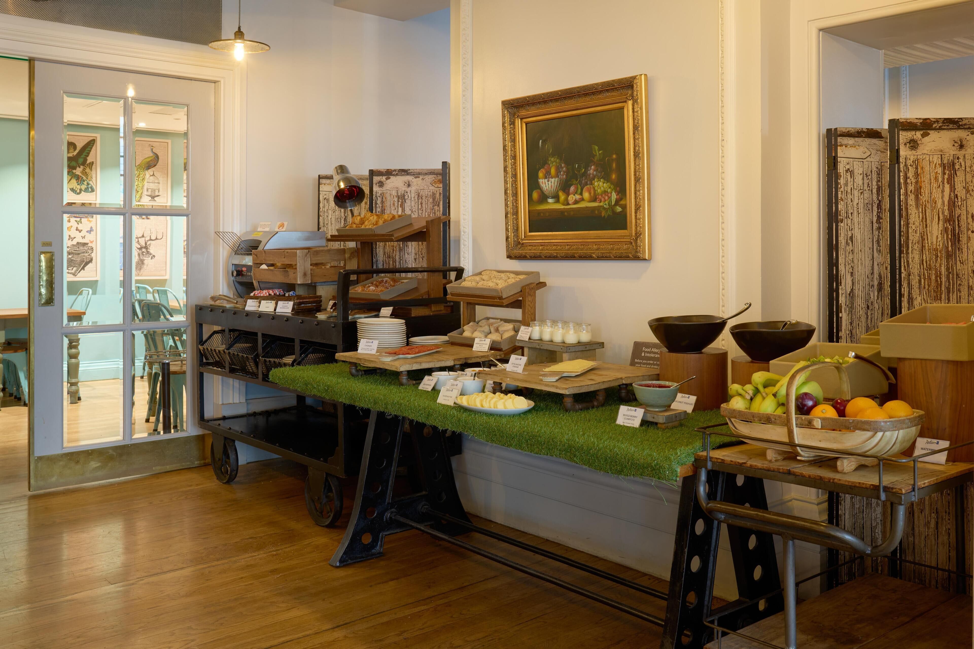 A buffet setup with various food items and a painting on the wall.