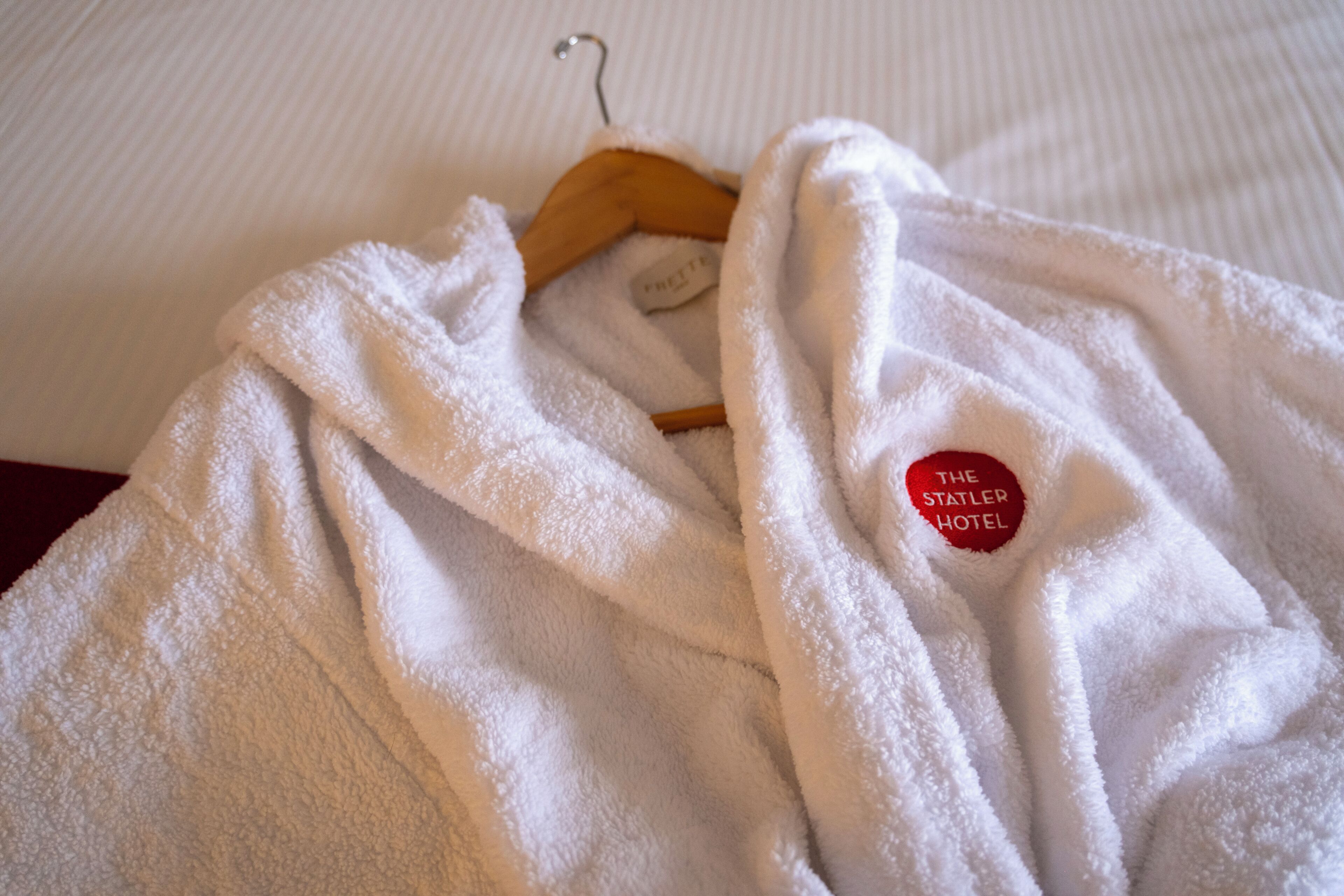A white robe with a tag on a wooden hanger.