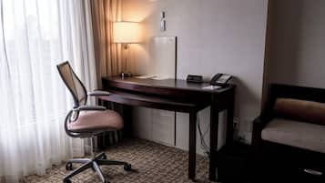 Habitació d'hotel amb escriptori, cadira, làmpada, telèfon i llit.