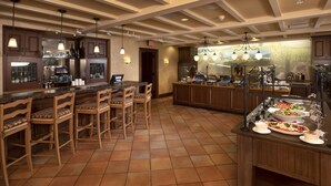 Een ruime keuken met een bar, houten stoelen en een buffetopstelling.