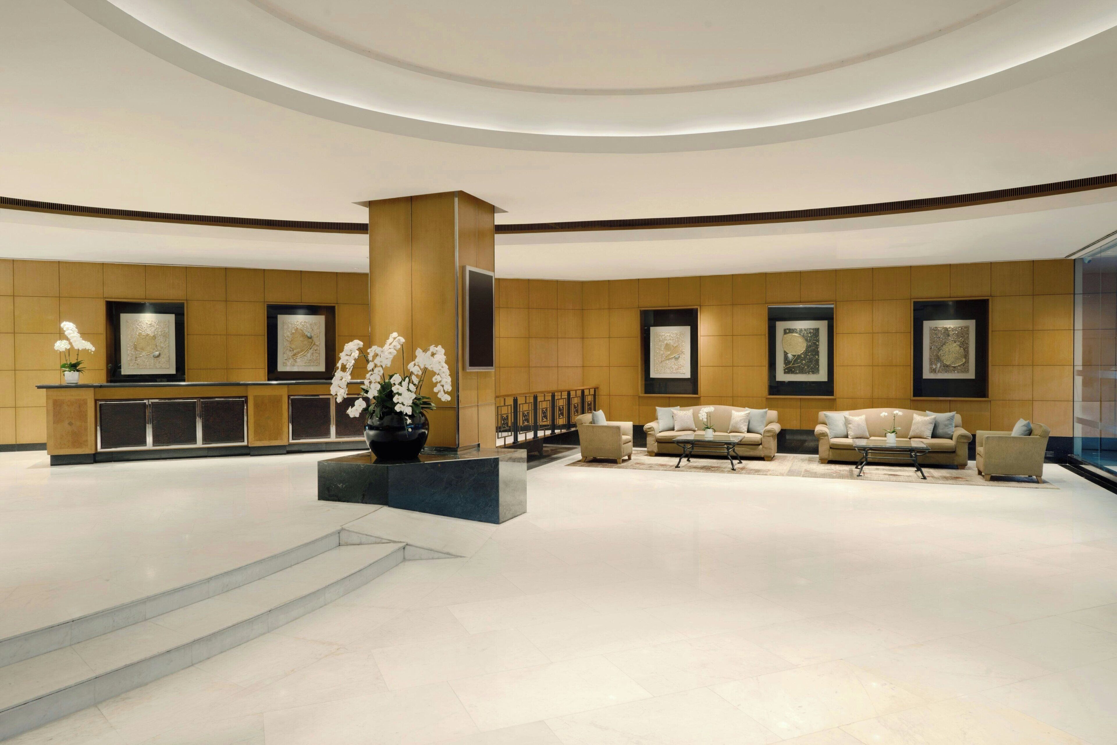 A spacious lobby with a reception desk, seating area, and artwork on the walls.