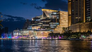 A modern hotel with a waterfront view, featuring a prominent glass facade and a unique architectural design with a sloped roof. - Royal Orchid Sheraton Riverside Hotel Bangkok (Bangkok)