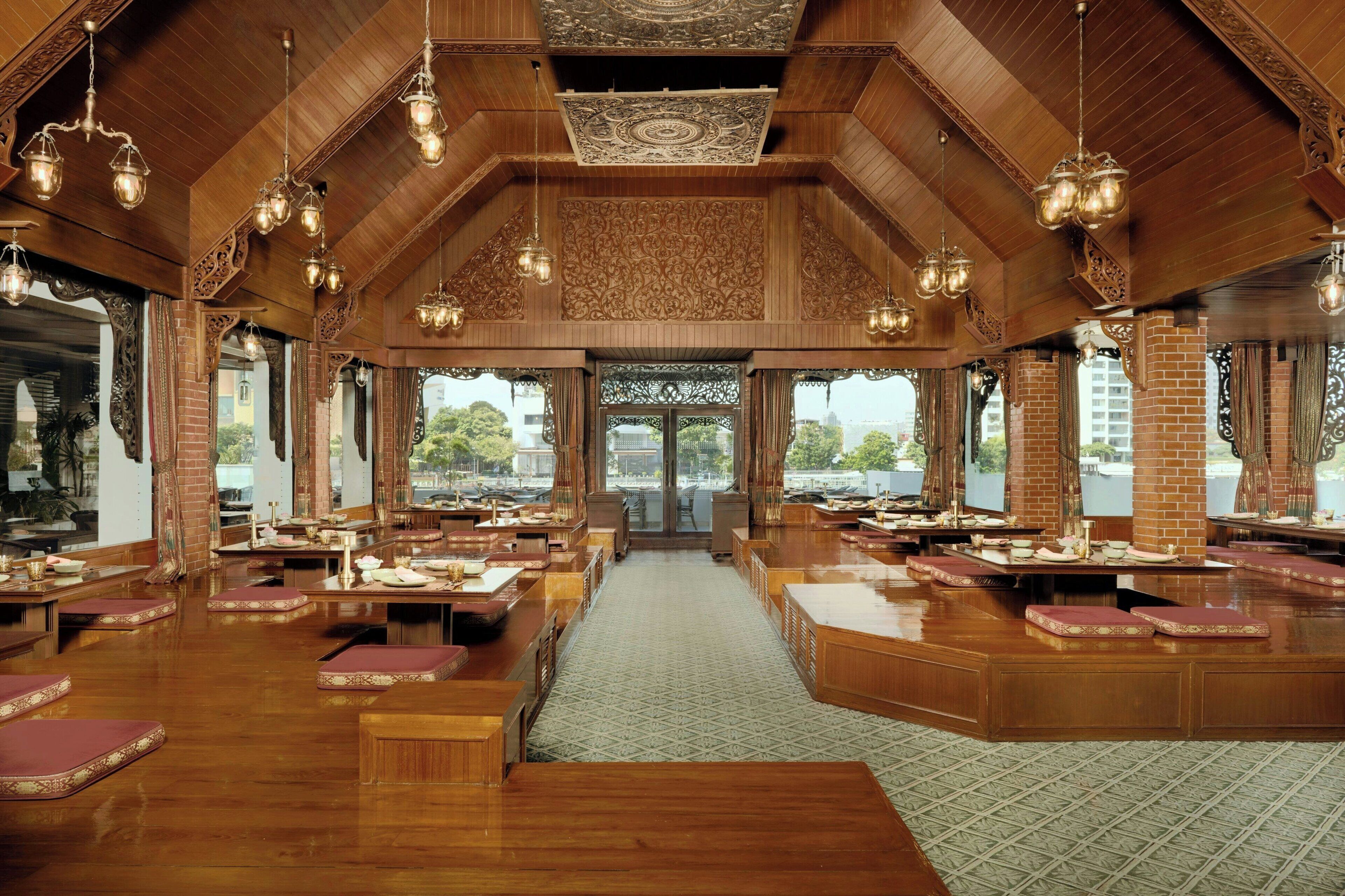 Un restaurant spacieux avec de hauts plafonds en bois, des lustres décoratifs et une allée centrale.