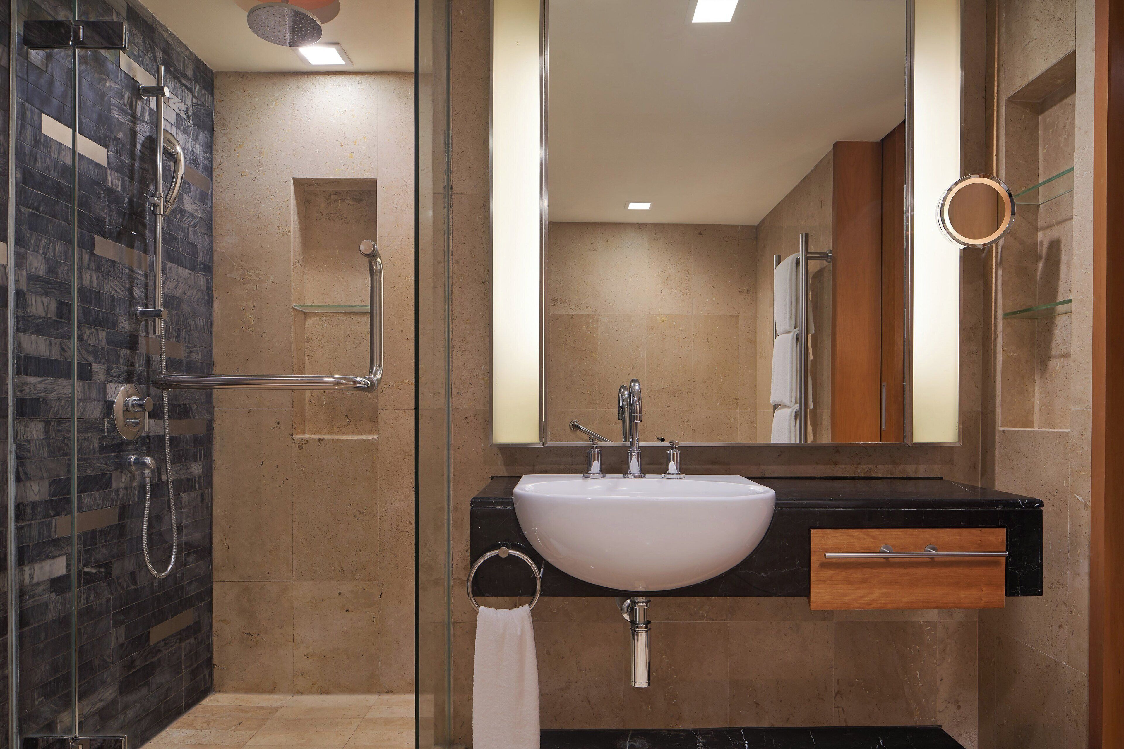 A modern bathroom with a glass-enclosed shower, a white sink, and a large mirror.