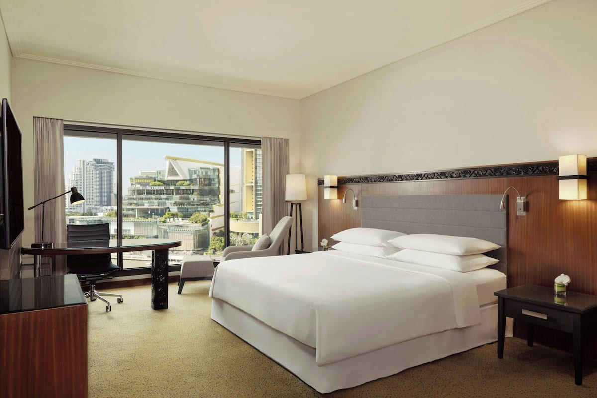 Una habitación de hotel con una cama grande, un escritorio, una silla, un televisor y vistas a la ciudad.