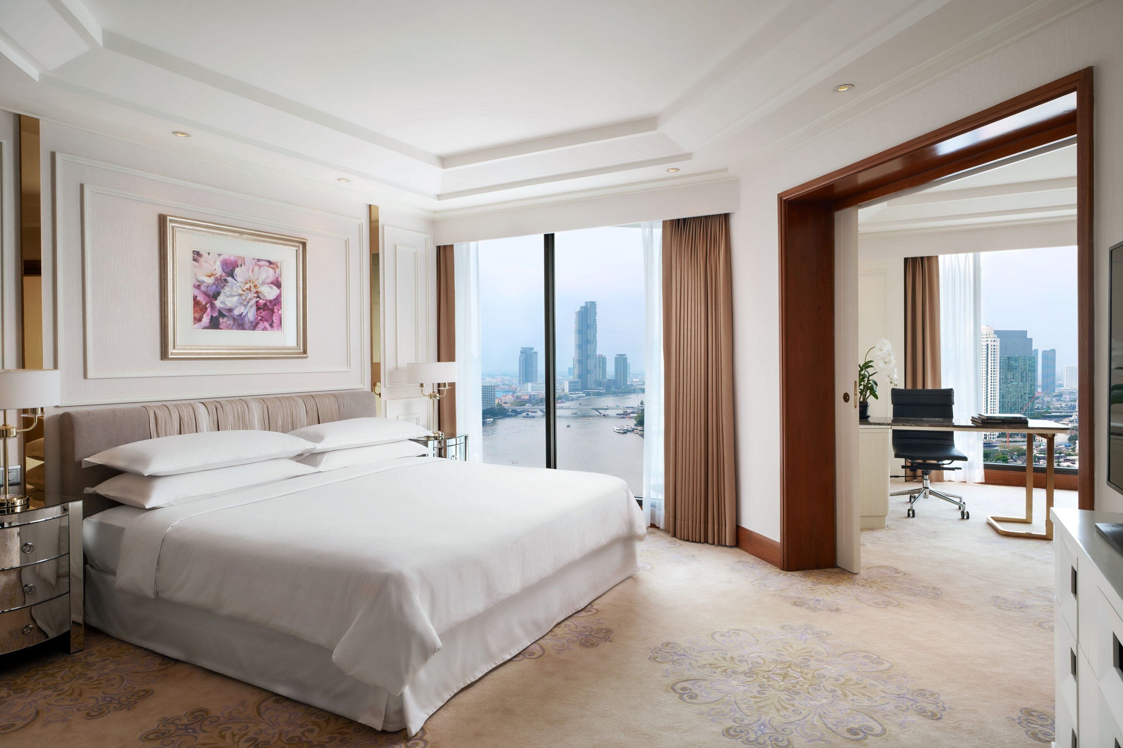 Ruime hotelkamer met een groot bed, een bureau en uitzicht op een stadsgezicht.