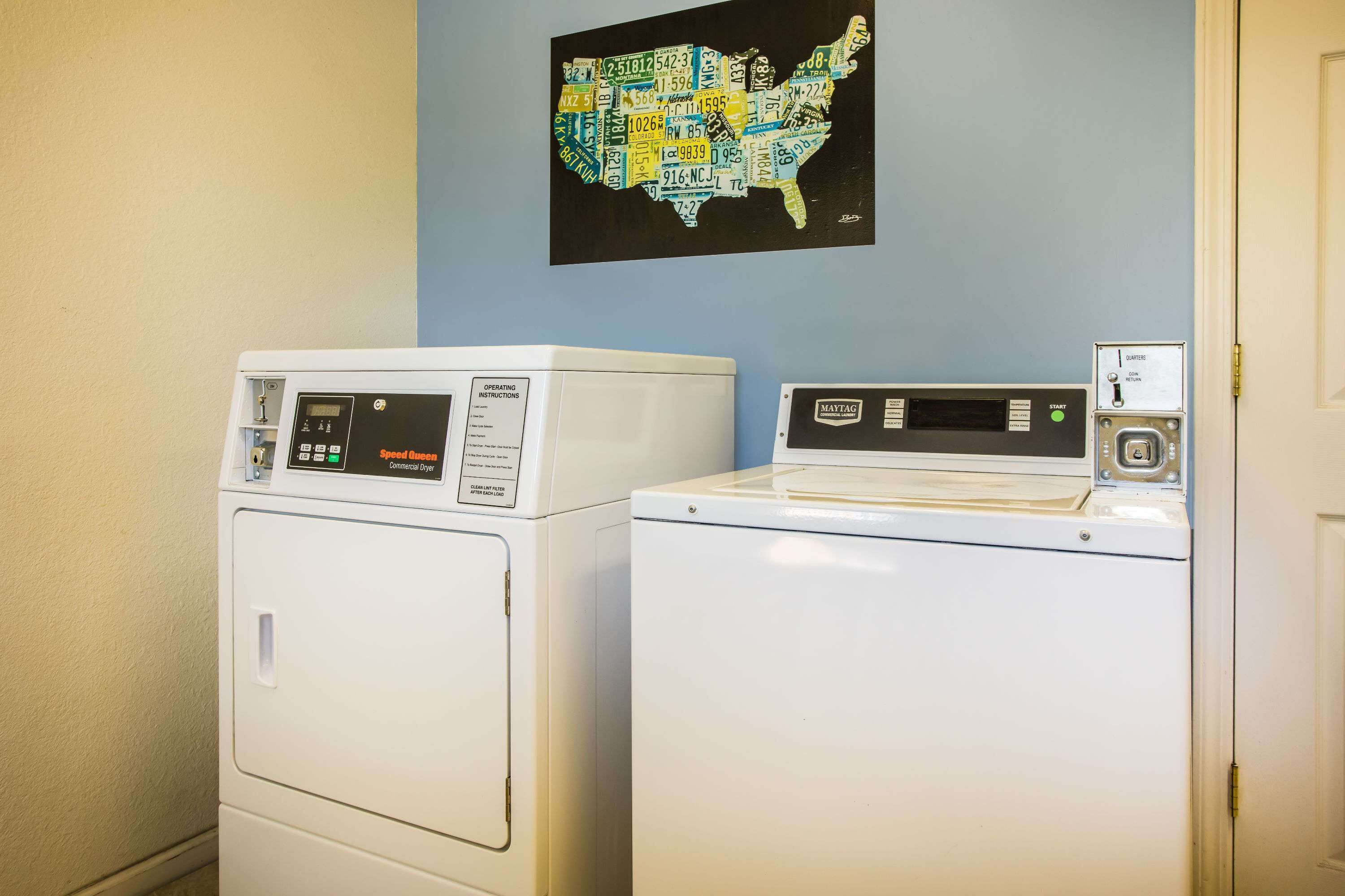 Two white front-loading washers in a laundry room with a map of the United States on the wall.